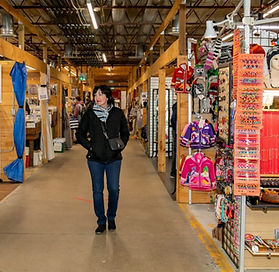 A woman walking down the isles of Peddlers Village Market Building admiring merchandise 