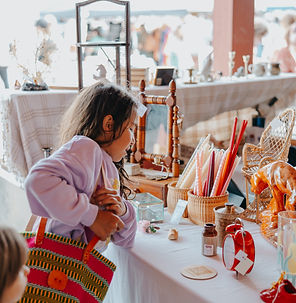 A young visitor browsing a table filled with antique wicker items  at St. Jacobs Market Open Air Antique Fair 