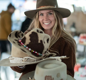 a vendor holding a selection of cowboy hats at Harvest Hoedown Event at St. Jacobs Farmers' Market 