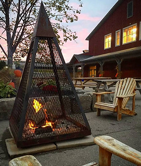Image of an enclosed fire pit surrounded by chairs in front of the market building 