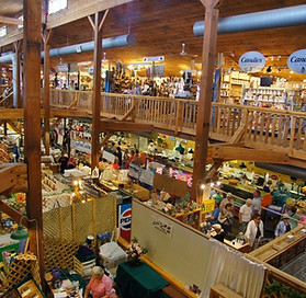 a view of an inside bustling indoor market building with diverse crowd browsing stalls looking down from the upper mezzanine 