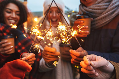 Group of friends holding sparklers and drinking hot beverages 