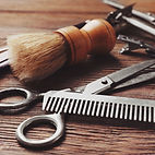 Several mens grooming accessories displayed on a wood counter at Revered For Men
