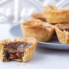 Delicious butter tarts neatly stacked on a plate with one in front with a bite out of it by Bake My Day