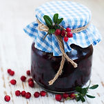A jar of homemade cranberry jam covered in blue and white checkered fabric from Kitchen Cuttings 