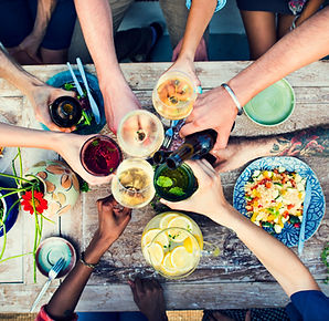 an overhead view of a group of people cheers' in the center of a table of food. With a text overlay " St. Jacobs Village"