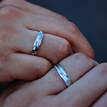 A couple holding hands displaying their wedding rings at Firstwater Jewelry