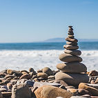 Calming Image of rocks stacked on a beach from Mindful Moods 