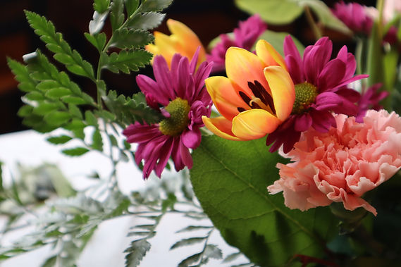 Close-up on flower arrangement from St. Jacobs Farmers Market Mother's Day Workshop which includes a yellow tulip and purple daisies. 