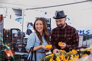 A couple customers laughing and admiring mini gourds outside of the Farmers' Market 