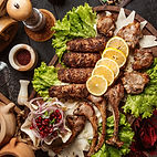 A selection of cooked meat dishes garnished with lemon and greens from Almadina Cuisine