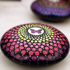 A beautiful Mandala painted on a small round stone by Riverbend Mandalas