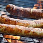 Sausages cooking on a grill over an open flame from Finest Sausage and Meat 