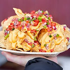 a delicious plate of nachos topped with cheese sauce, tomatoes, jalapenos, and onions from Ray Woodey's Craft Chippery 